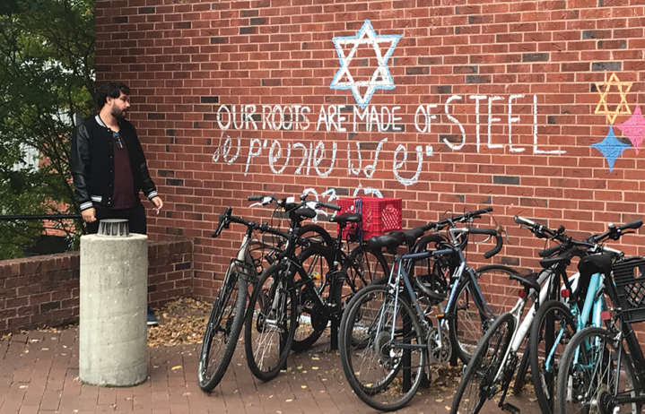 A student stands next to ICC, where the words "Our roots are made of steel" are scrawled in chalk. Image courtesy of Natalie Ise, The Hoya.